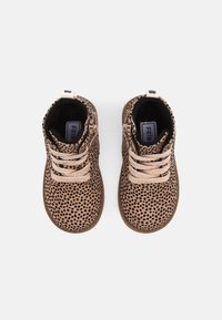 Hnědé semišové kotníkové boty s černými skvrnami, zdobené béžovými tkaničkami, polstrovaným interiérem a hnědou gumovou podrážkou. Doplněné o zadní poutko.