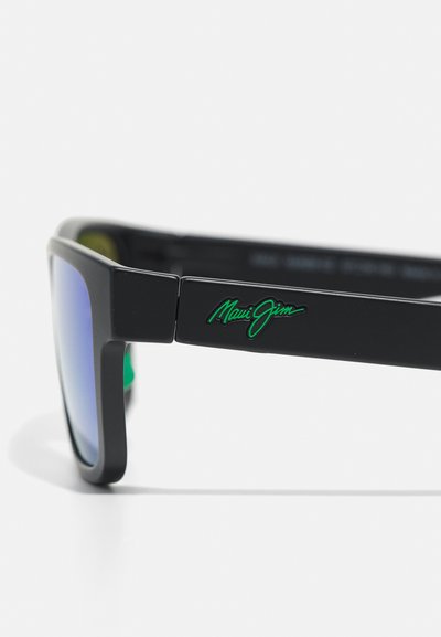 Black sunglasses with a matte finish, blue gradient lenses, square design, and a green Maui Jim logo on the side arm.