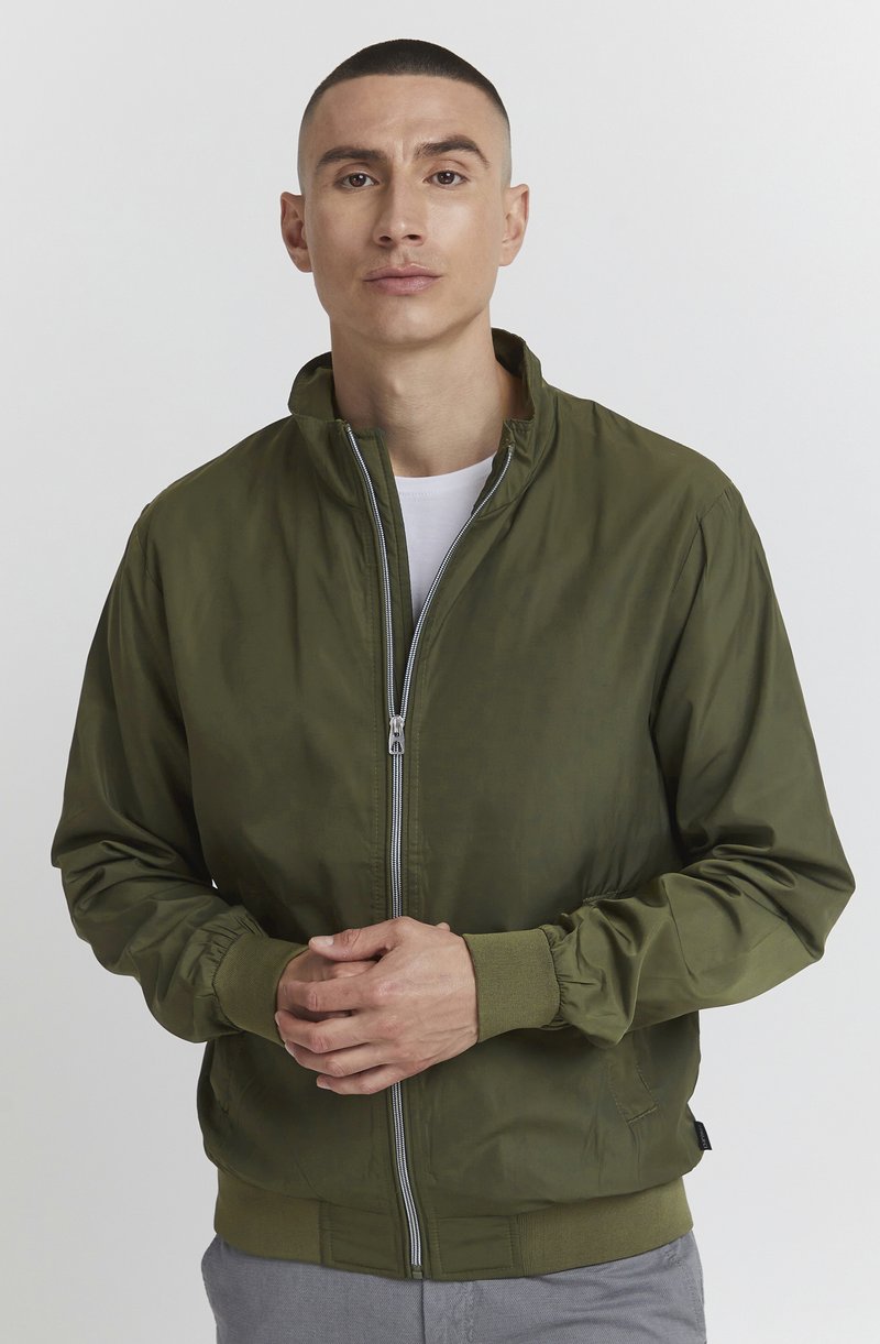 Olivegrüner Bomberjacke aus glattem Stoff, mit Stehkragen, Frontreißverschluss sowie elastischen Bündchen und Saum.