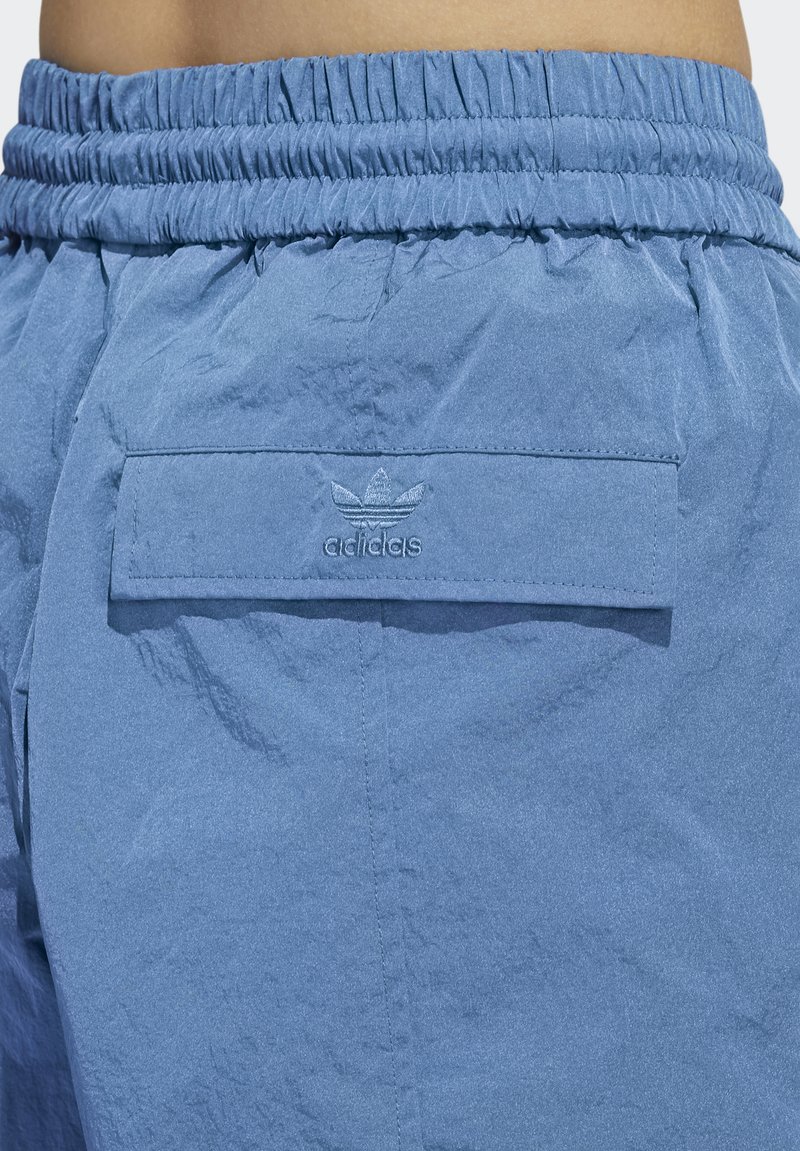 Lichtblauwe, lichte shorts met een elastische tailleband, met een kleine achterzak en geborduurd Adidas-logo. Textuurdetails zijn zichtbaar.