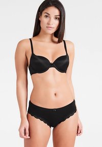 Schwarzes Dessous-Set mit einem glatten, gepolsterten BH mit verstellbaren Trägern und einem passenden Slip mit Spitzenbesatz und einer Schleifenverzierung.