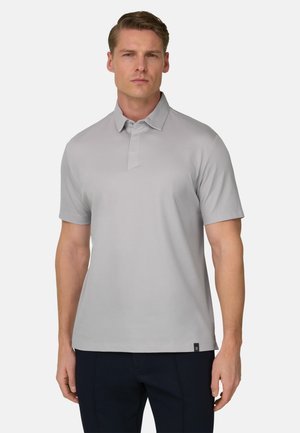 Polo gris clair avec un col classique, des manches courtes et un design minimaliste. Présente une petite étiquette sur l'ourlet.