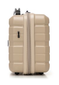 Valigia rigida di colore beige chiaro con superficie testurizzata, forma rettangolare, una cerniera centrale, tirazip nera e ruote in plastica.