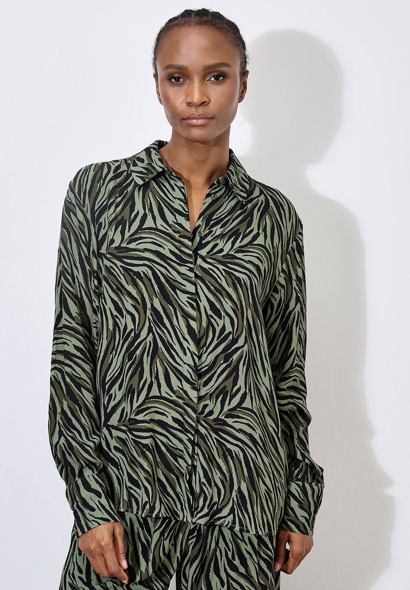 Green and black patterned blouse featuring a collar and long sleeves, made from a smooth material with a loose fit.