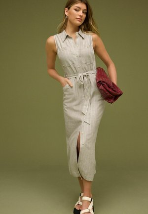 Długa, jasnoszara sukienka w paski z paskiem do wiązania, guzikami i bocznymi rozporkami. Zestawiona z ciemnoczerwoną, teksturowaną kopertówką.