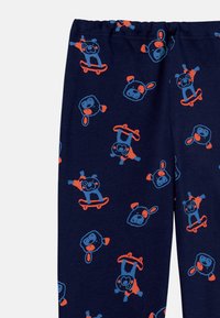 Cotton pajama pants in navy featuring a playful pattern of skateboarding animals in blue and orange. Elastic waistband for comfort.