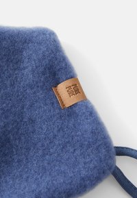 Pochette en tissu en laine douce bleue avec une étiquette en cuir marron embossée "PURE PURE" et un cordon bleu sur un fond blanc.
