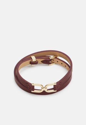 Ceinture en cuir marron à double tour avec boucle et fermoir dorés, posée à plat sur un fond blanc.