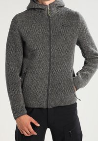 Szara dzianinowa bluza z zamkiem błyskawicznym, z teksturowanym wzorem, dopasowanym krojem i dwiema bocznymi kieszeniami. Posiada kaptur i prosty detal z logo.
