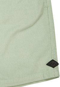 Lichtgroene ribstoffen shorts met een gestructureerd oppervlak en een zwart label van stof met een golfontwerp nabij de zoom.