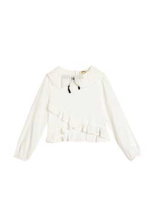 Blouse blanche à manches longues avec un design à volants, col rond et nœud noir. Tissu lisse avec un froufrou texturé le long de l'ourlet.