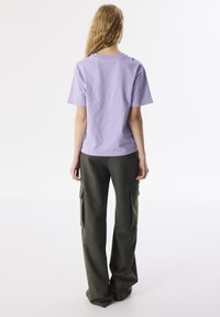 Lila katoen t-shirt met korte mouwen en ronde hals, gecombineerd met losse olijfgroene cargo pantalons met zijzakken.
