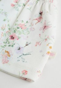 Tela con estampado floral en colores pastel, con ribete texturizado, con flores rosas e ilustraciones de hadas caprichosas.