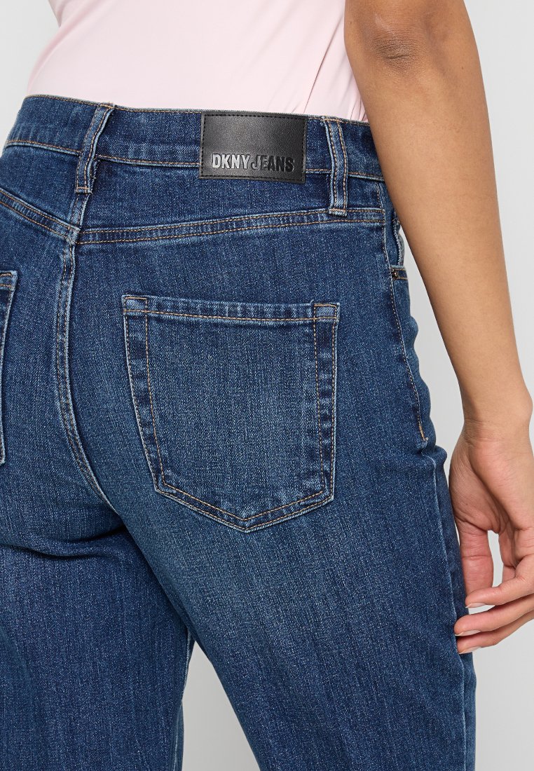 Hellblaue Denim-Jeans mit einem mittelhohen Bund, ausgestattet mit einem schwarzen Leder-Logo-Patch und zwei Gesäßtaschen mit Stichakzenten.