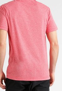 Red athletic t-shirt made from a lightweight, textured fabric. Short sleeves and a crew neckline with a subtle heathered pattern.