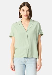 Lichtgroene blouse met korte mouwen, voorzien van een textuur patroon, knopen aan de voorkant en een ontspannen pasvorm, aangevuld met een notch kraag.