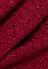 Tissu tricoté bordeaux avec des motifs texturés et de petits détails en dentelle, présentant des rayures horizontales et verticales pour une dimension supplémentaire.