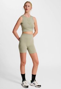 Jasnozielony crop top oraz pasujące do niego wysokowysokie spodenki rowerowe wykonane z elastycznego materiału, zaprojektowane z myślą o komforcie i swobodzie ruchów. Ozdobione delikatnymi wzorami.