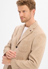 Beige Cordblazer mit vertikaler Rippung, einfacher Knopfverschluss, Reverskragen und einer Brusttasche. Die strukturierte Stoffqualität sorgt für visuelles Interesse.