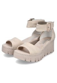 Beige platform sandals with an open toe and ankle strap, featuring a textured sole and layered, adjustable strap detail.