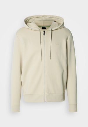 Hellbeiger Kapuzenpullover mit Reißverschluss, Kordelzug an der Kapuze, gerippten Bündchen und Saum, mit einem minimalistischen Logo auf der Brust. Glatte Stoffstruktur.