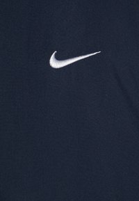 Navy blue Nike t-shirt with a white embroidered swoosh logo on the upper left. Fabric displays a smooth, soft texture.