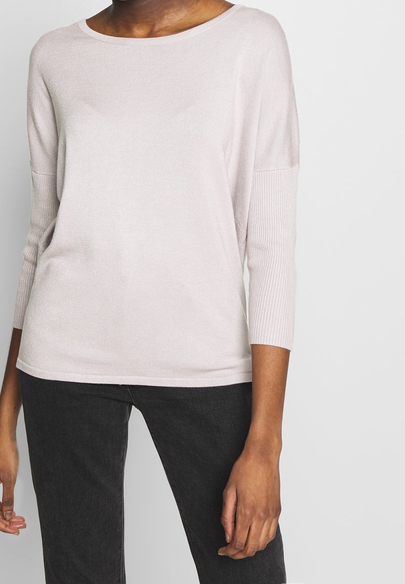 Light pink, ribbed knit sweater with three-quarter sleeves and a rounded neckline. Soft texture and relaxed fit design.