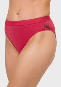 Rote Baumwollbikinislips mit glatter Textur, ausgestattet mit einem breiten Bund und einem kleinen Logoetikett in kontrastierender Farbe an der Seite.
