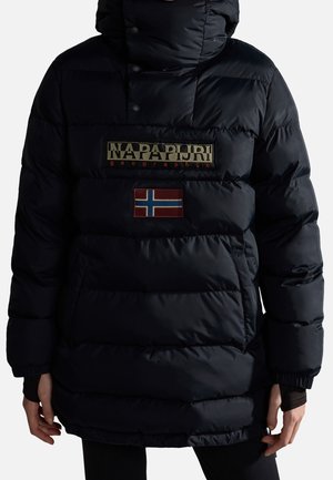 Person trägt eine schwarze gesteppte Jacke mit Kapuze, Napapijri-Logo und norwegischem Flaggenpatch auf der Brust.