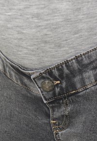 Grå denimjeans med knappstängning, med en sydd midja och subtil textur. Tyget är något slitet för en avslappnad look.