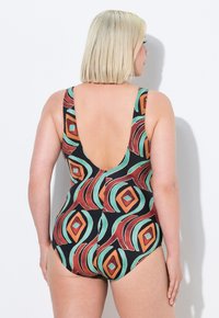 Maillot de bain une pièce avec un design à dos bas, fabriqué dans un tissu extensible avec un motif géométrique multicolore en orange, turquoise et noir.