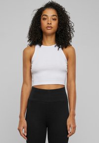 Witte geknipte tanktop met een hoge hals en slanke pasvorm, gecombineerd met hoge zwarte leggings; gladde stof en minimalistisch ontwerp.