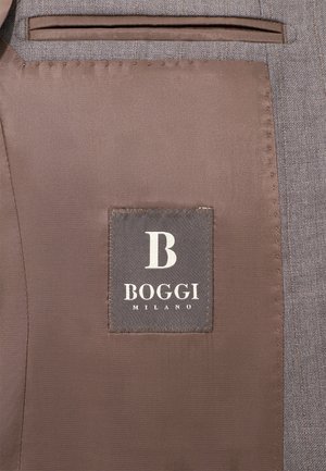 Grau gestepptes Innenfutter einer Jacke mit einem braunen Etikett, das das "BOGGI MILANO"-Logo und ein großes "B" zeigt. Angenehme Textur, saubere Nähte.