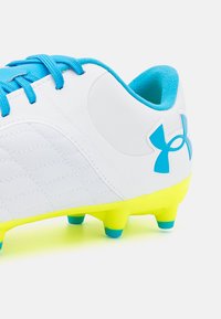 Scarpa da calcio bianca con lacci blu e logo, caratterizzata da una tomaia testurizzata e suola gialla brillante con tacchetti arrotondati per una migliore trazione.