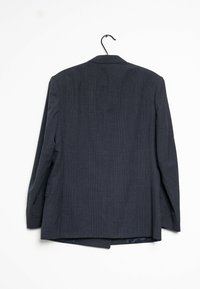 Blazer bleu marine avec un motif à carreaux subtil, à boutonnage simple, et manches longues. Suspendu sur un cintre noir contre un fond blanc.