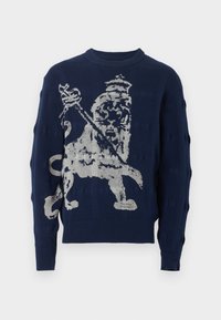 Suéter de punto azul marino con un diseño en la parte delantera de un león blanco que lleva una corona y sostiene un cetro, mangas largas y cuello acanalado.