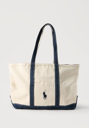 Beige Canvas-Tragetasche mit dunkelblauen Trägern, unterem Rand und einem kleinen bestickten Polo-Spieler-Logo auf der Vorderseite.