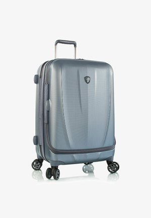 Zilveren harde koffer met een gestructureerd oppervlak, een uitschuifbare handgreep en vier dubbele wielen voor stabiliteit en wendbaarheid.