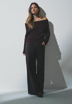 Burgundy off-shoulder neulepaita, leveät mustat housut ja tummat ballerinat. Pehmeä rakenne ja rento istuvuus, pitkät hihat ja minimaliset yksityiskohdat.