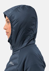 Marineblau isolierte Jacke mit strukturiertem Kapuzenaufsatz, aus glattem Material und mit durchgehendem Reißverschluss. Mit Logodetail auf der Brust.