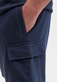Marineblaue Cargo-Shorts aus weichem Baumwollmaterial, mit einer Seitentasche und einem flachen Bund für eine lässige Passform. Die Nähte sind sorgfältig verarbeitet.