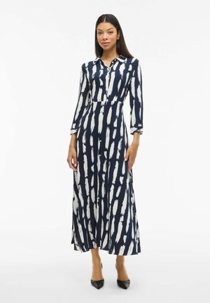 Robe maxi à motif bleu marine et blanc, avec un col, des manches longues et une fermeture à boutons. Présente une silhouette évasée qui fluidifie la silhouette.