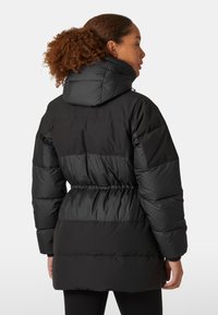 Zwarte pufferjack met een capuchon, voorzien van een cinched taille, gequiltte secties en ribgebreide manchetten. Glad, glanzend stoffen textuur.