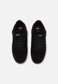 Black suede sneakers with black laces, rubber sole, and a white GLOBE logo tag on the tongue. Rounded toe and minimalistic design accents.