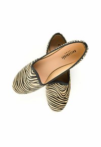 Scarpe slip-on con stampa zebra, con tomaia in tessuto, bordi elastici neri e una soletta beige liscia. Suole piatte per una calzata comoda.