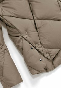 Beige pufferjack met een diamantgevoerd ontwerp. Voorzien van drukknoopsluiting en een rits, met een gladde, lichtglanzende textuur.