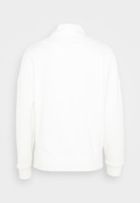 Sudadera blanca con cuello alto, hombros caídos y puños de canalé. Textura suave, corte relajado, diseño minimalista, sin patrones visibles.