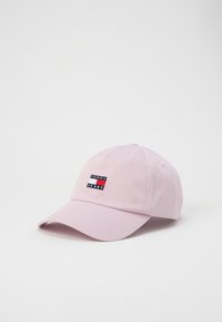 Pink cotton baseball cap with a curved visor and embroidered logo patch featuring red, white, and blue colors. Adjustable strap at the back.