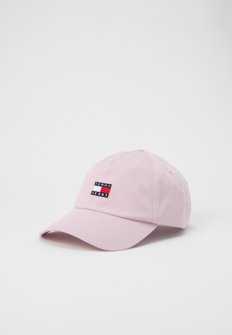 Pink cotton baseball cap with a curved visor and embroidered logo patch featuring red, white, and blue colors. Adjustable strap at the back.