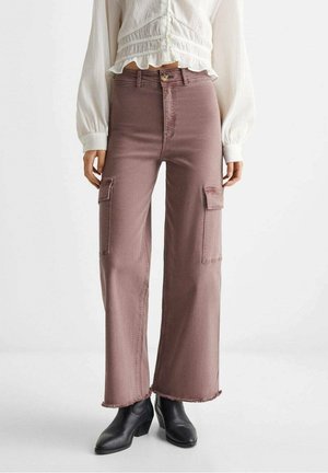 Pantalon cargo taille haute mauve avec poches à rabat, ourlets effilochés, associé à un chemisier blanc à manches longues et des bottines noires.
